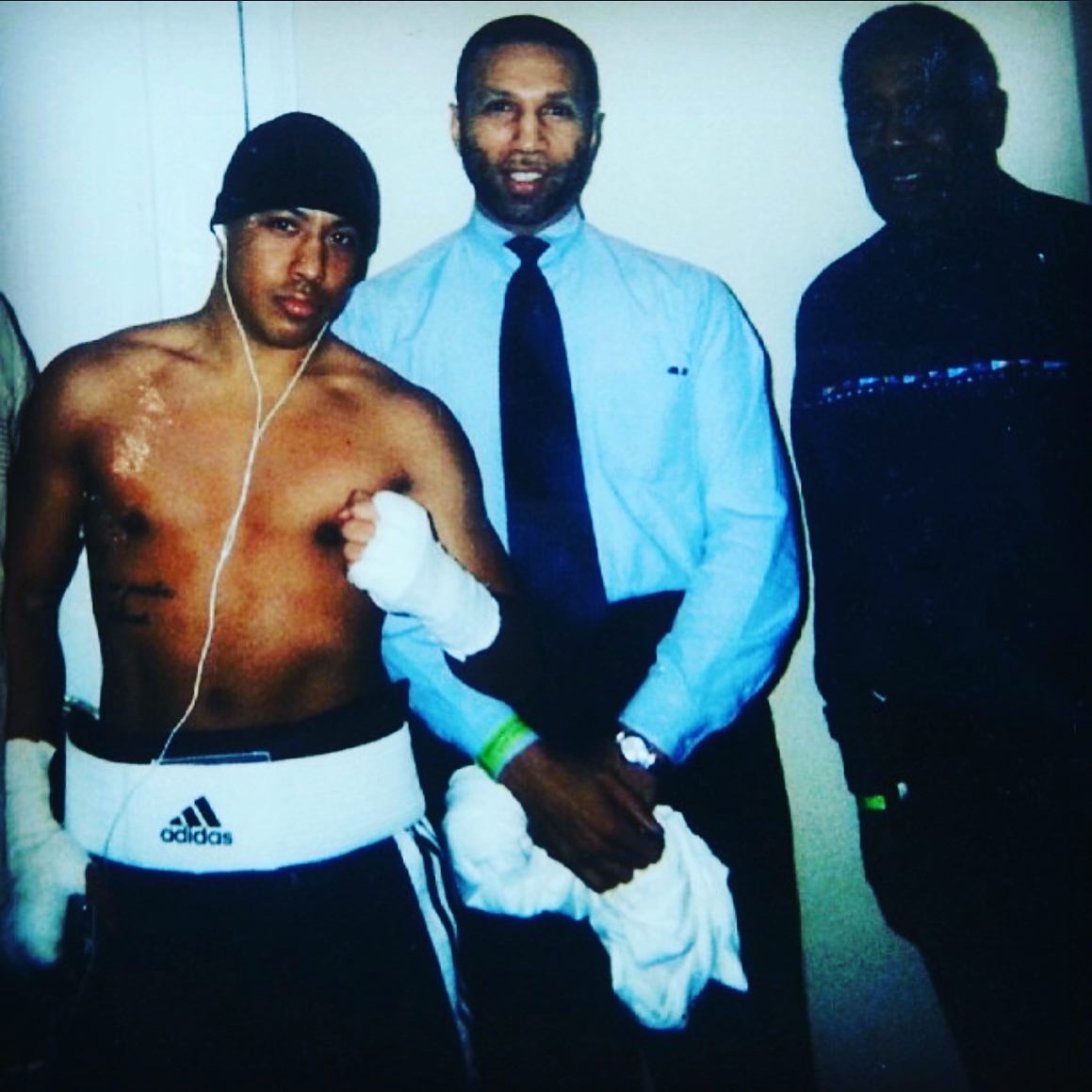 Boxer with taped hands posing with two men after a fight