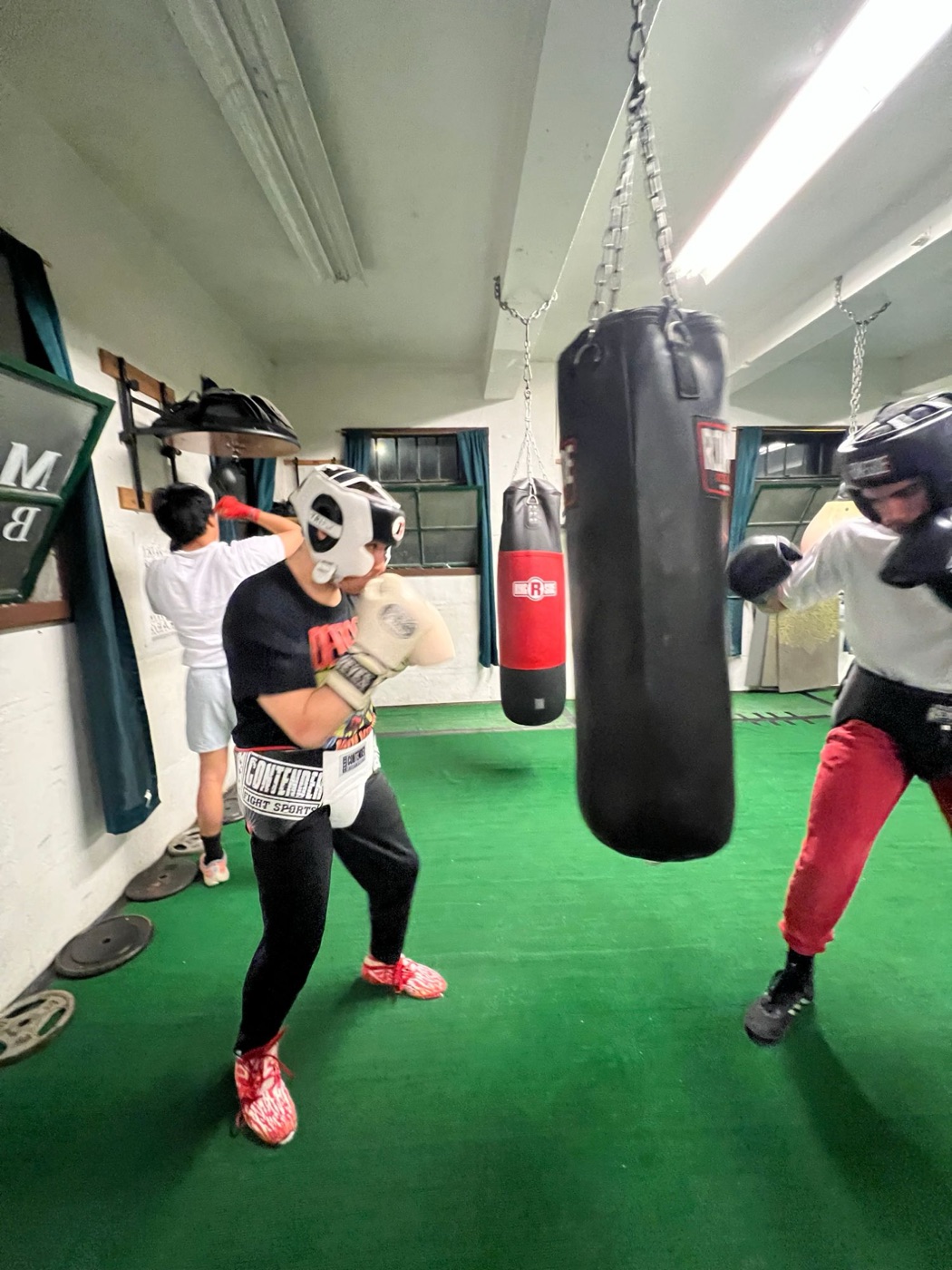 Boxers in headgear working on the heavy bags at the ChampionBreed gym