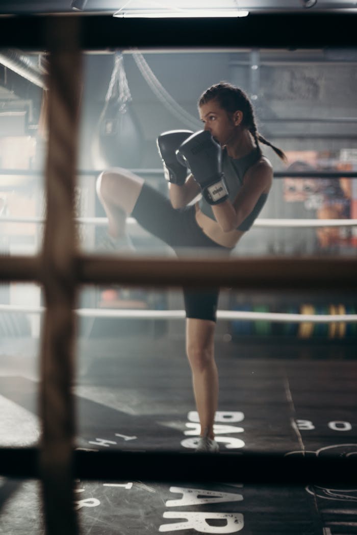 Determined young woman practicing kickboxing in a gym with focused stance.